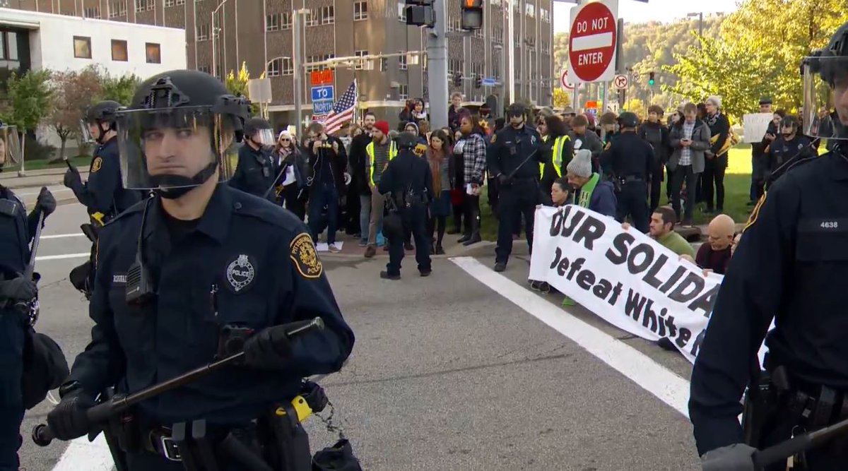 Protesters blocking a street with a banner reading Our solidarity will defeat White Nationalists are being arrested in downtown Pittsburgh ahead of President Trump's visit this afternoon